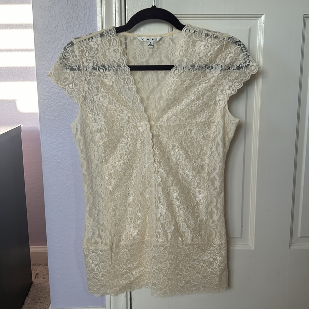 Cabi cream lace top with cap sleeves, and 3 fasteners below V neck.
